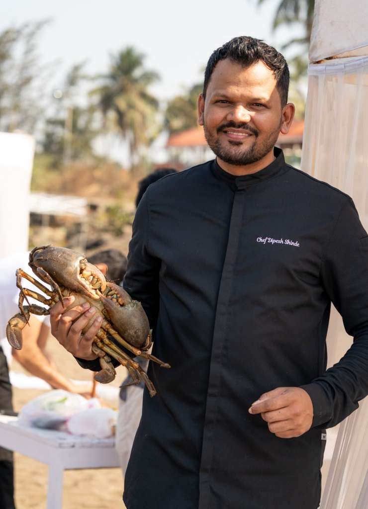 Chef Dipesh Shinde holding a live crab on the coast